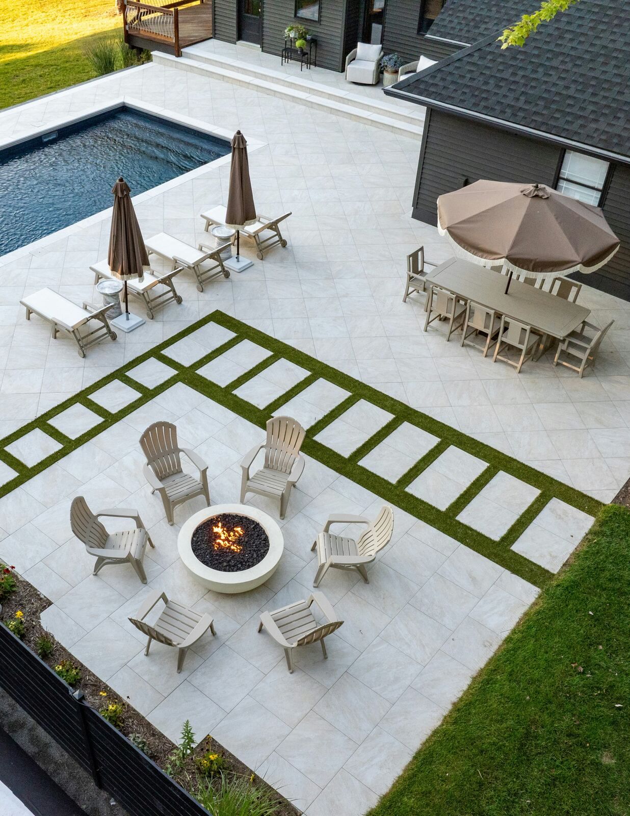 Turf strips inlaid between pavers on a patio with a fire pit